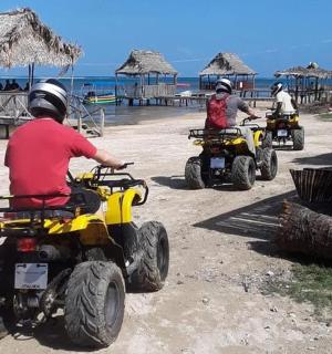 three people riding on atvs on the beach