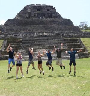 a group of people jumping in front of a pyramid