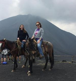 two women riding horses in front of a mountain