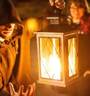 a man in a nun costume holding a lantern