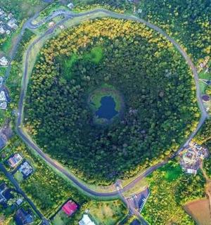 an aerial view of a park with a road and a lake