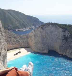 a woman sitting on a cliff overlooking a beach