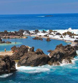 a swimming pool with rocks in the ocean