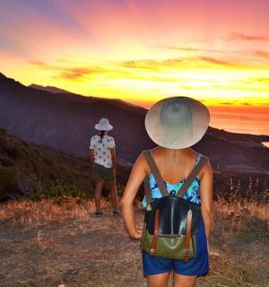 a woman walking on a hill with a man watching the sunset