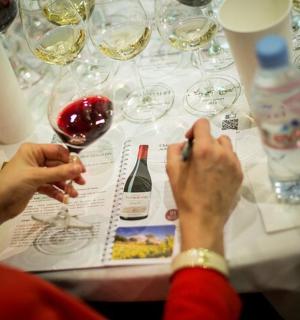 坐在桌边，手里拿着酒杯的人