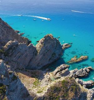 an aerial view of a rocky shore with blue water