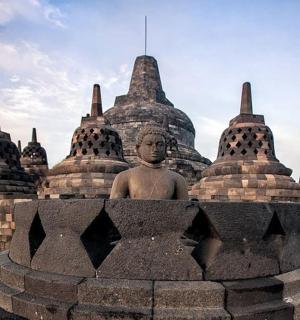 a statue sits in front of a stone building