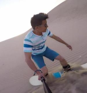 a man standing on a surfboard in the sand