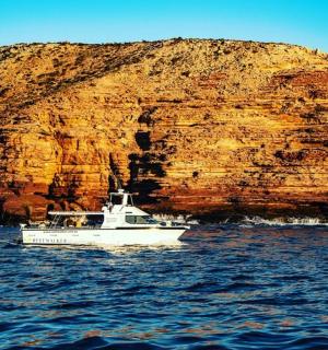 悬崖边水中的一艘白色小船