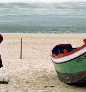 一位女士站在海滩上的一艘船旁