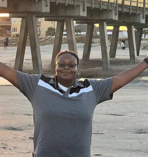 a woman standing on the beach with her arms up