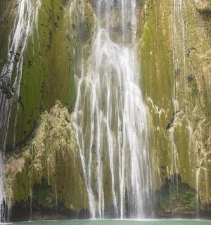 a waterfall on the side of a mountain with green water