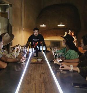 a group of people sitting around a bar with bottles of wine