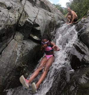a girl is laying on a rock in a waterfall