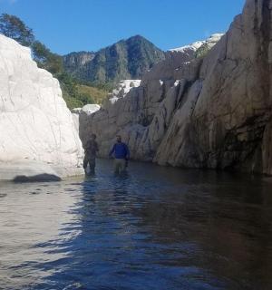 two people standing in a river between rocks