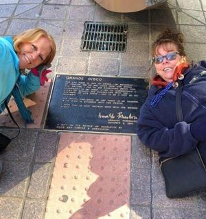 两名妇女站在地上的一块牌匾旁边