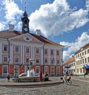 un grande edificio con una torre dell'orologio e una fontana