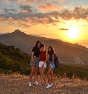 夕暮れの山の頂上に立つ3人の女の子