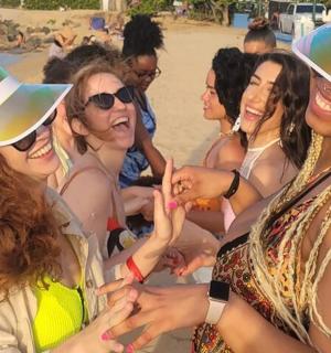 Skupina žen v kloboucích na pláži