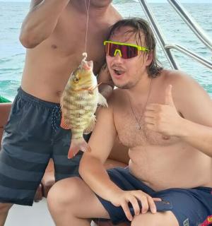 two men sitting on a boat holding a fish