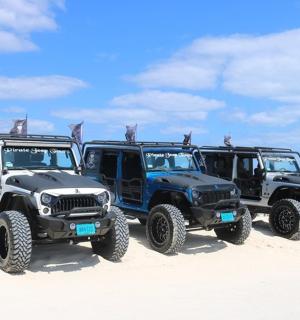 three jeepneys parked on a sandy beach