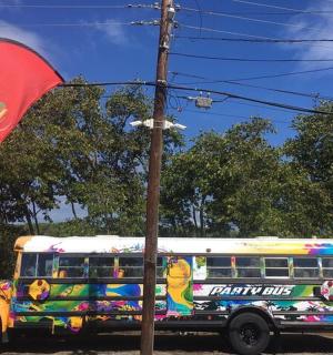 litríkur skólabíll lagður við hliðina á fána