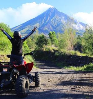 isang tao sa isang four wheeler sa isang maruming kalsada na nakataas ang kanilang mga braso