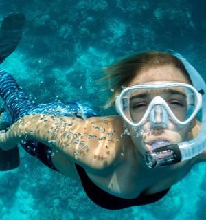 a woman wearing a snorkel and a gas mask in the water