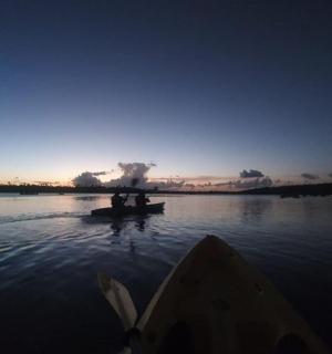 two people in boats on a lake at sunset