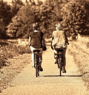two people riding bikes down a dirt road