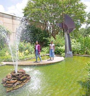 dva muži stojící před fontánou v rybníku