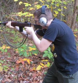 a man in headphones holding a gun in the woods
