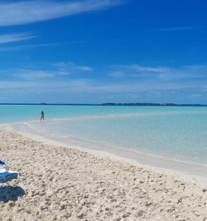 a blue umbrella on a beach with a man in the distance