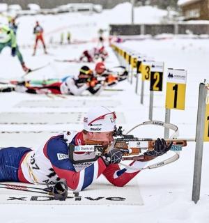 a man laying on the snow while holding a gun