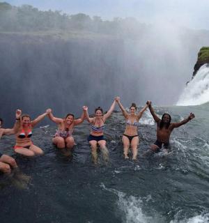 skupina lidí ve vodě před vodopádem