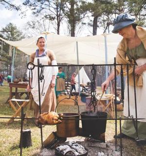 一位女士站在一位男士旁边，在烤架上烹饪食物