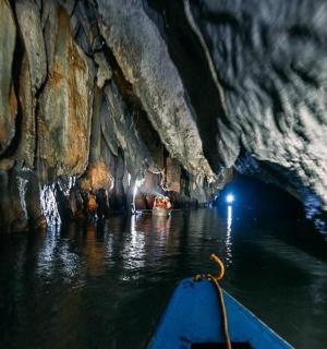 a boat in a cave with water and rocks
