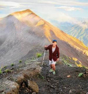 ชายคนหนึ่งยืนอยู่บนยอดเขาพร้อมกับว่าว