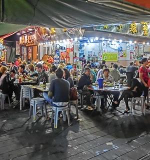 一群人晚上坐在市场里的桌子旁