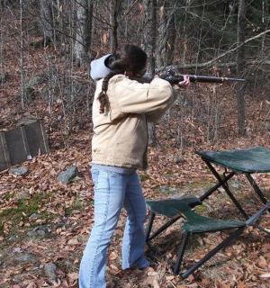 a woman aiming a gun at a table