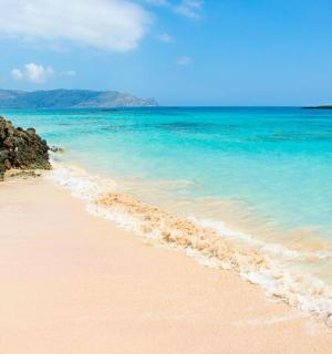 písečná pláž s modrou vodou a skalami