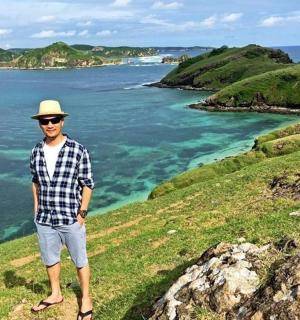 一名男子站在海边的一座小山上