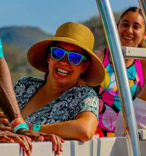 жінка в капелюсі та сонцезахисних окулярах сидить на човні