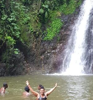 three people in the water in front of a waterfall