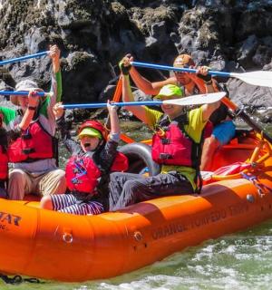 一群人坐在河里的橙色木筏上