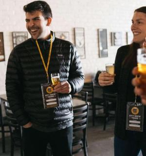 a group of people standing around holdingints of beer