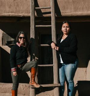 two women are standing next to a ladder