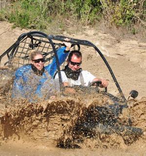 two people riding in an off road vehicle in the mud