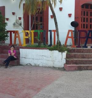 一位女士坐在标志牌前的长椅上