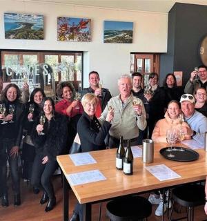 一群人围坐在桌边，手拿酒杯摆姿势拍照